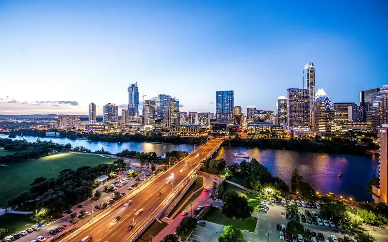 Downtown Austin skyline at dusk with a highway bridge and the lake in front